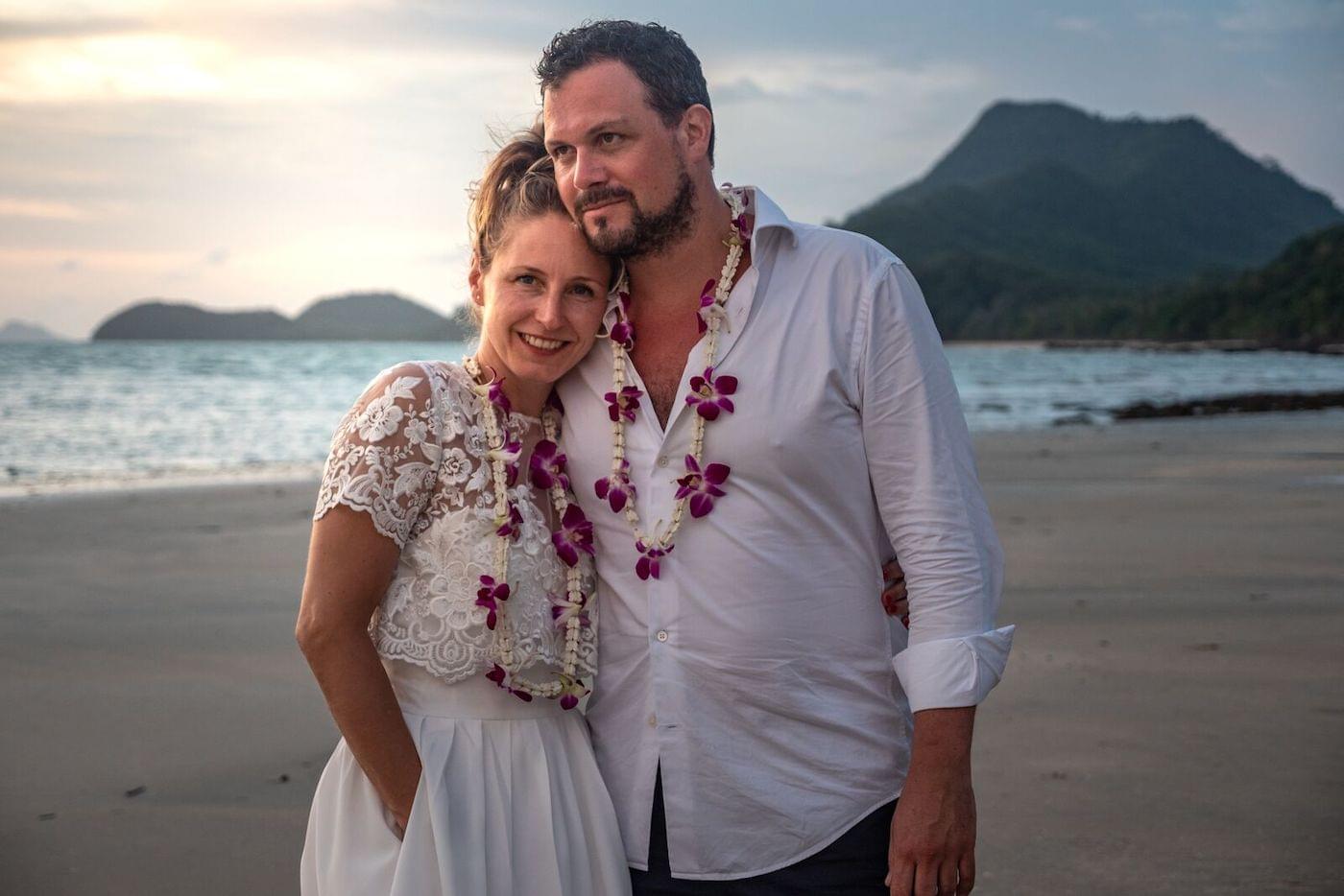 Bride and groom wearing garlans on beach