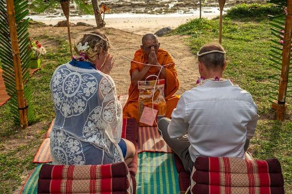 Couple being married by a monk near the beach
